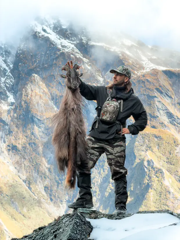 Holding up a caped bull tahr on a snowy ridge