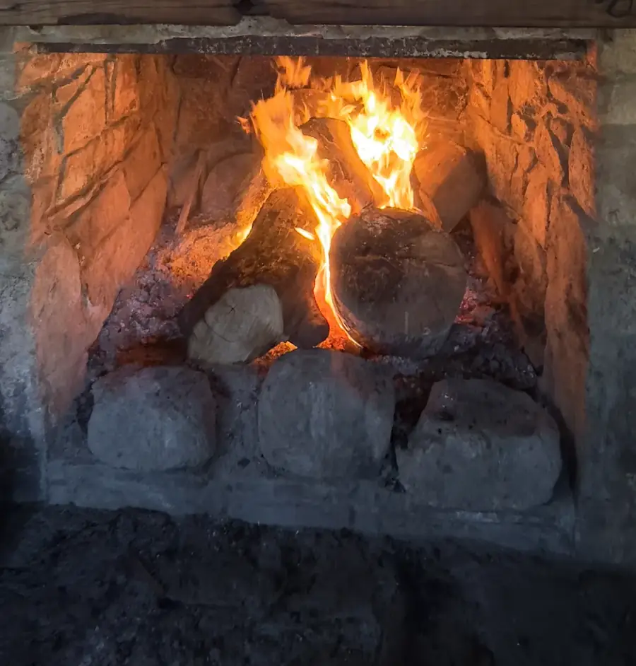 An open fire burning with tall flames in a stone hut fireplace